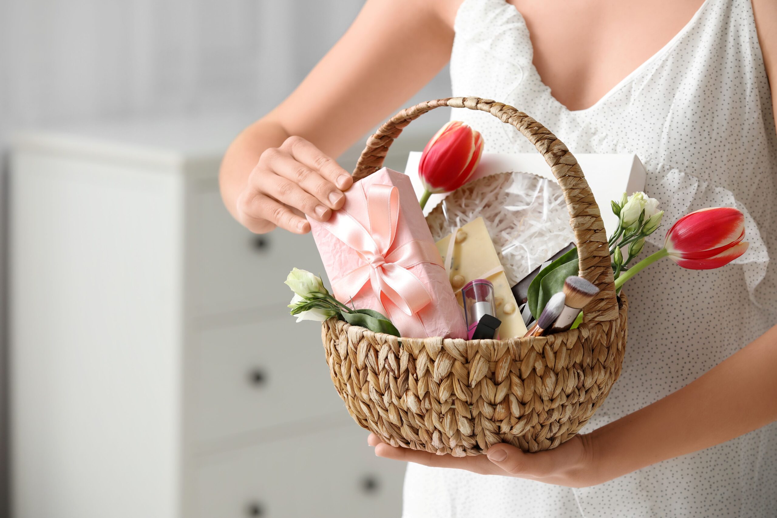 Frau überreicht einen liebevoll gestalteten Präsentkorb mit Blumen und Geschenk